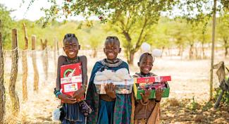 Children smiling and holding shoebox gifts