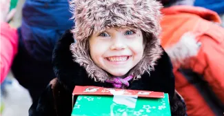child in fluffy hat smiling with shoebox in Moldova