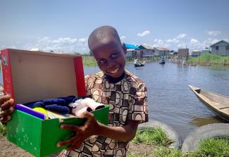 boy smiling with shoebox by river