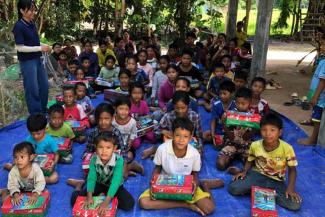 CAMBODIAN BOYS AND GIRLS WAIT IN ANTICIPATION FOR THE MOMENT THEY CAN OPEN THEIR GIFT-FILLED SHOEBOXES.