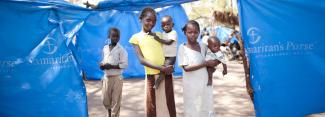 children in front of tarp shelters