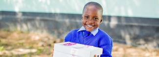 Boy in Zimbabwe smiles with white shoebox gift