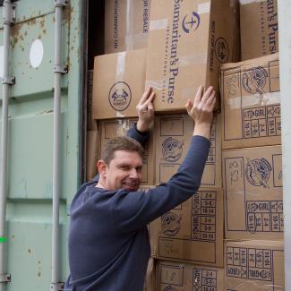 volunteer lifts carton of shoeboxes