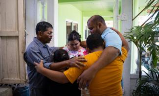 Pastor Rigoberto Mejia (left) prays with the Peña family, who placed their faith in Jesus Christ after their children received Operation Christmas Child shoebox gifts at Key Baptist Church in El Cayo, Honduras.