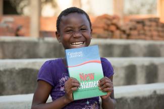 girl smiling with new testament Bible