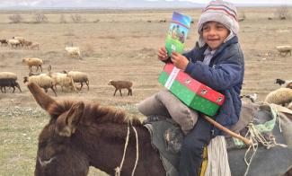 Young boy on a donkey holding shoebox