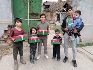 group of children of various ages holding shoebox gifts