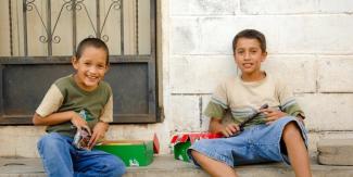 Two boys sitting on a step smiling with shoebox gifts