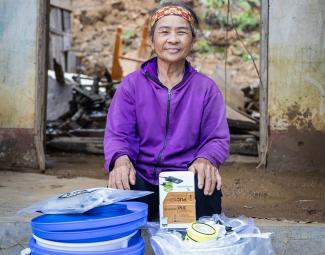 Tran sits behind her supplies she received from Samaritan’s Purse–a household water filtration system, a solar-powered light, and a kitchen kit.