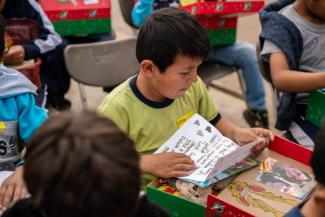 A boy appreciates the letter and photo inside his shoebox gift that personalized it just for him.